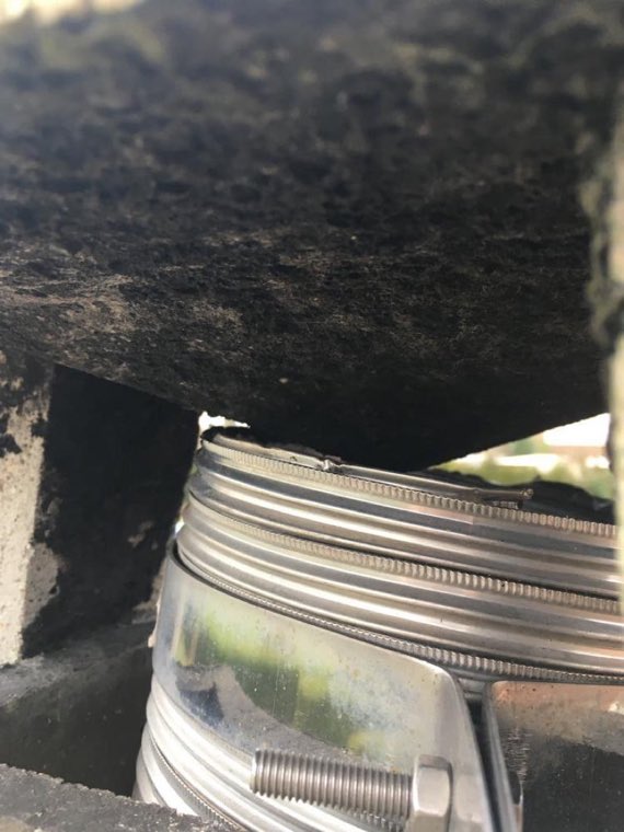 Gros plan sur un tubage inox flexible engagé dans un conduit de cheminée